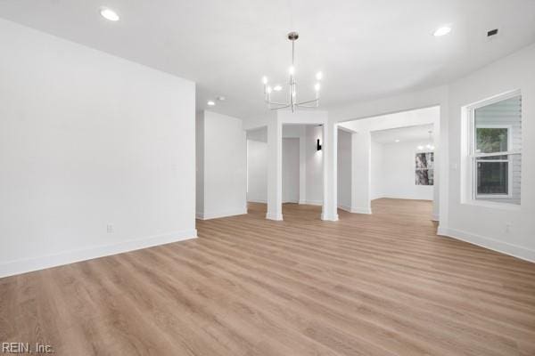 unfurnished living room with recessed lighting, a notable chandelier, light wood-style floors, and baseboards