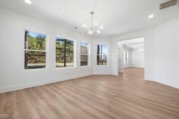 empty room featuring visible vents, baseboards, light wood-style floors, and an inviting chandelier