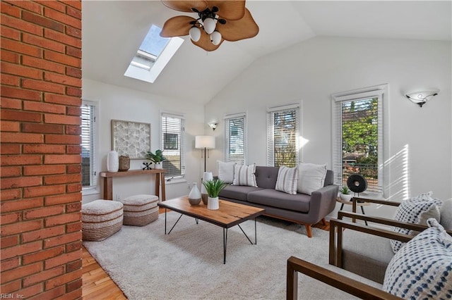 living room with a ceiling fan, vaulted ceiling with skylight, and wood finished floors