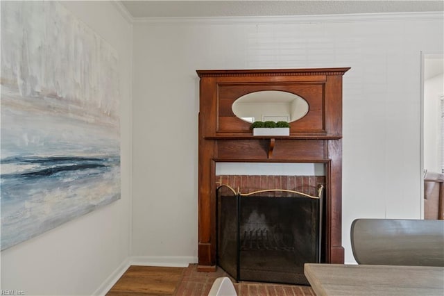 living room with baseboards, a brick fireplace, wood finished floors, and crown molding