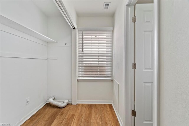 laundry room with laundry area, visible vents, baseboards, and wood finished floors