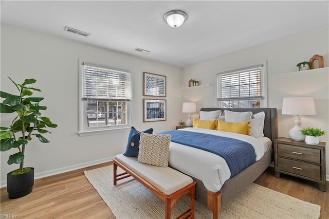 bedroom with visible vents, baseboards, and wood finished floors