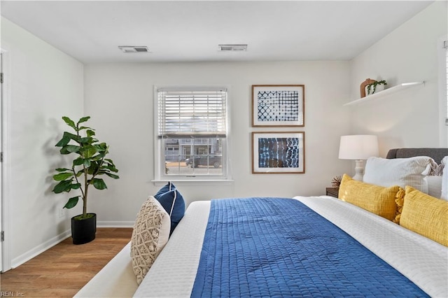 bedroom featuring wood finished floors, visible vents, and baseboards