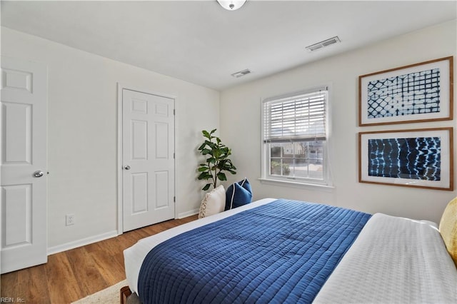 bedroom with visible vents, baseboards, and wood finished floors