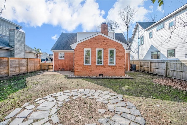 rear view of property with a fenced backyard, a chimney, crawl space, central AC, and brick siding