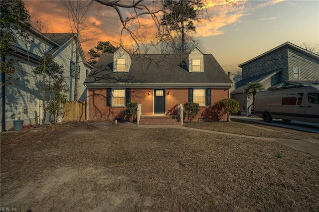 rear view of property featuring a shingled roof and brick siding