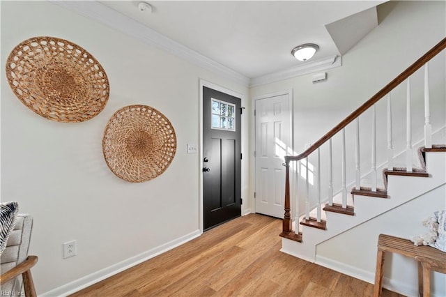 foyer entrance with ornamental molding, light wood-style floors, stairway, and baseboards