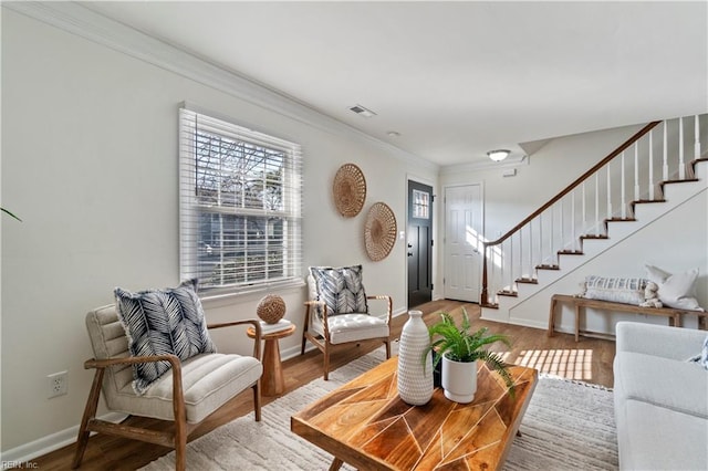 living area with baseboards, visible vents, wood finished floors, stairs, and crown molding