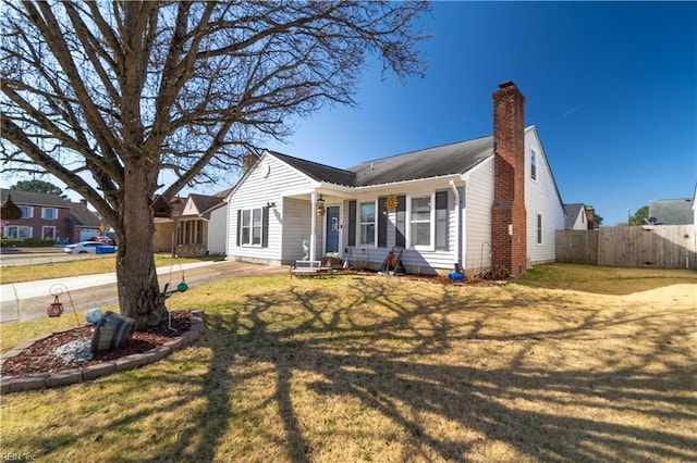 view of front of house with a front lawn, fence, and a chimney