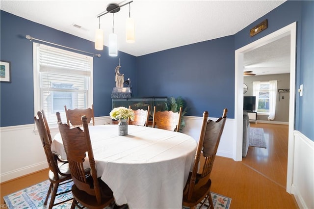 dining room featuring visible vents, wood finished floors, wainscoting, and a textured ceiling