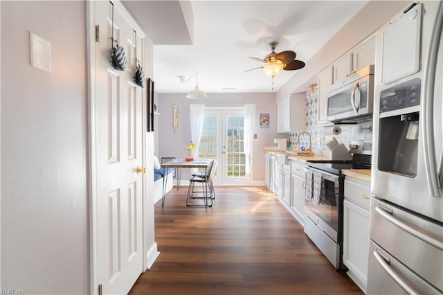 kitchen with stainless steel appliances, dark wood-style floors, white cabinets, and light countertops