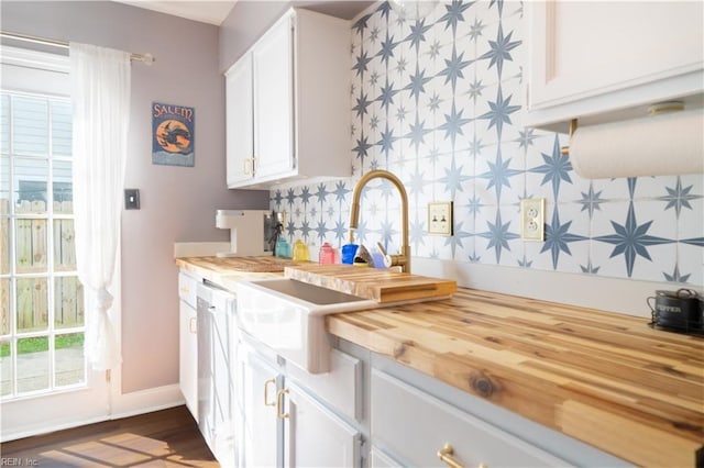 kitchen featuring a sink, tasteful backsplash, butcher block countertops, and white cabinets