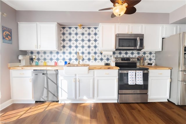 kitchen with dark wood-style floors, a sink, butcher block countertops, stainless steel appliances, and tasteful backsplash