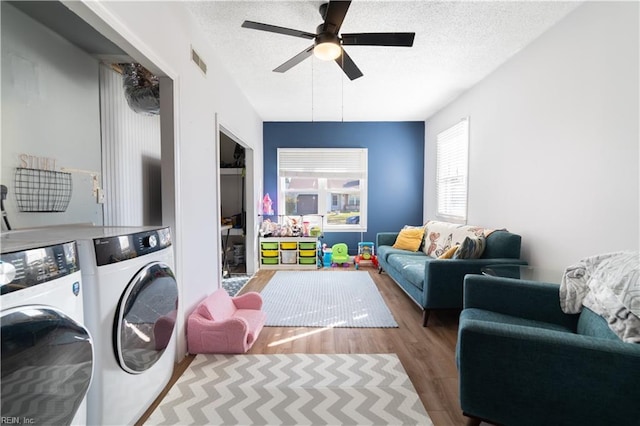 laundry room with washing machine and clothes dryer, visible vents, laundry area, wood finished floors, and a textured ceiling