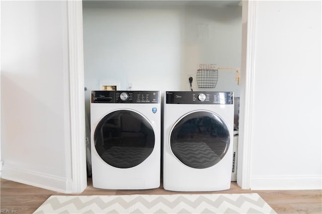 laundry area featuring laundry area, washer and dryer, baseboards, and wood finished floors