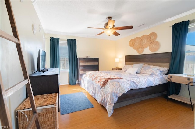 bedroom featuring a ceiling fan, wood finished floors, and ornamental molding