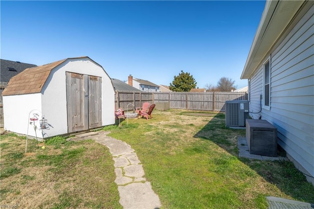 view of yard with an outbuilding, central AC unit, a fenced backyard, and a shed