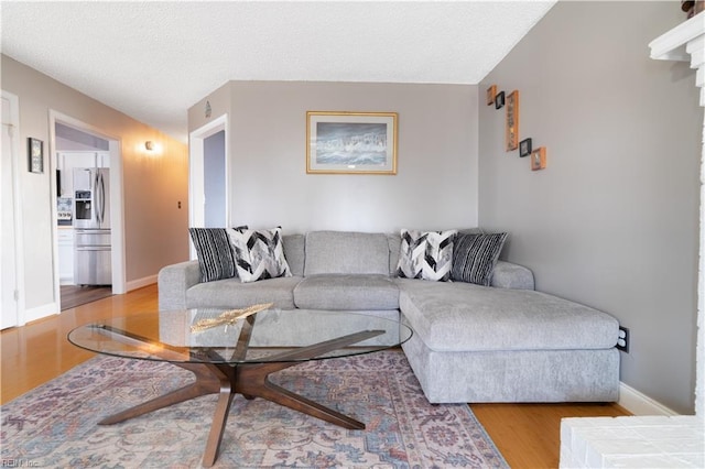 living area with baseboards, a textured ceiling, and wood finished floors