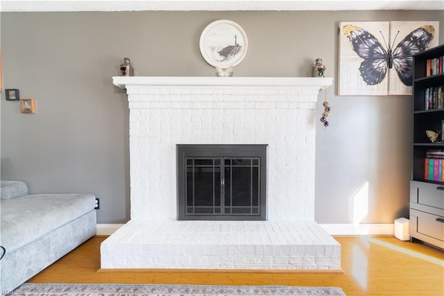 living area with wood finished floors, a fireplace, and baseboards