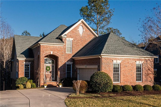 traditional home with a garage, driveway, a shingled roof, and brick siding