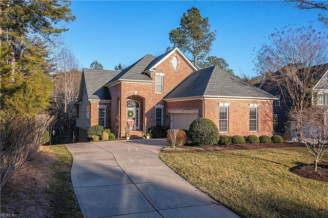 traditional home featuring an attached garage, brick siding, a shingled roof, driveway, and a front yard