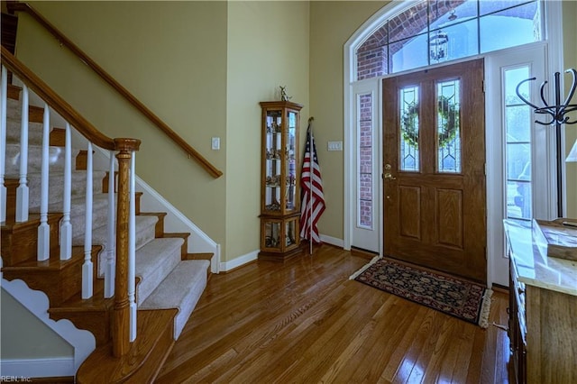 foyer entrance with stairway, baseboards, and wood finished floors