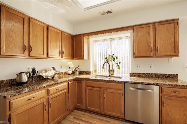 kitchen featuring light wood finished floors, visible vents, a sink, dark stone countertops, and dishwasher