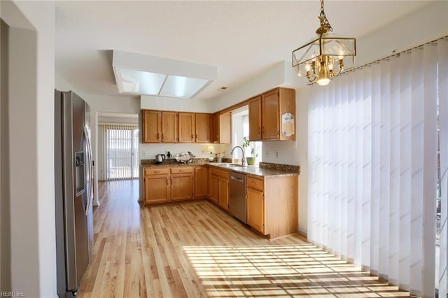 kitchen featuring a chandelier, stainless steel appliances, a sink, light wood-style floors, and brown cabinetry