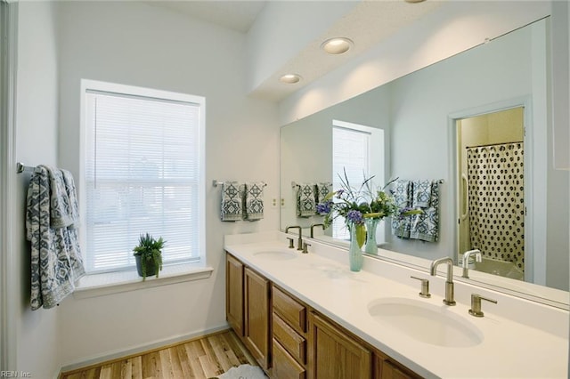 full bathroom with double vanity, wood finished floors, a sink, and curtained shower