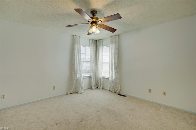 carpeted spare room with baseboards, visible vents, ceiling fan, and a textured ceiling