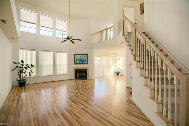 unfurnished living room with a fireplace, wood finished floors, a wealth of natural light, and a ceiling fan