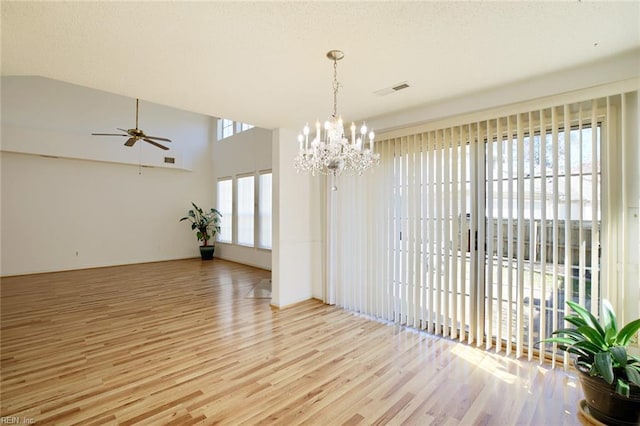 unfurnished room with visible vents, light wood-style flooring, a textured ceiling, and ceiling fan with notable chandelier