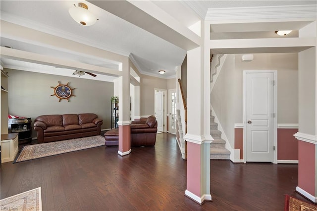 living area with dark wood-style floors, stairway, ornamental molding, a ceiling fan, and ornate columns