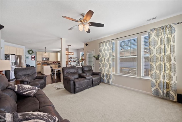 living area with baseboards, visible vents, a ceiling fan, light colored carpet, and a textured ceiling