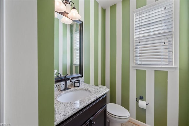 bathroom with vanity, toilet, and wallpapered walls