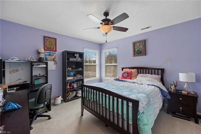 bedroom featuring a textured ceiling, carpet flooring, visible vents, and a ceiling fan