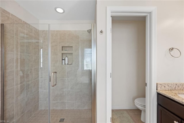 bathroom with a stall shower, vanity, toilet, and tile patterned floors