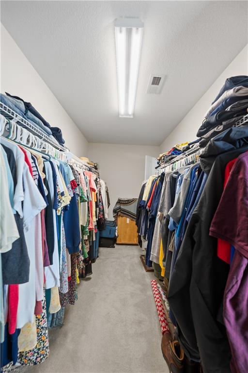 spacious closet with visible vents and light colored carpet