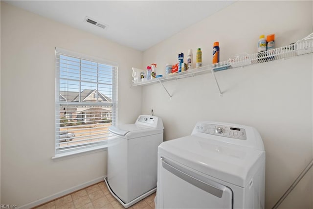 clothes washing area featuring washing machine and dryer, laundry area, visible vents, and baseboards