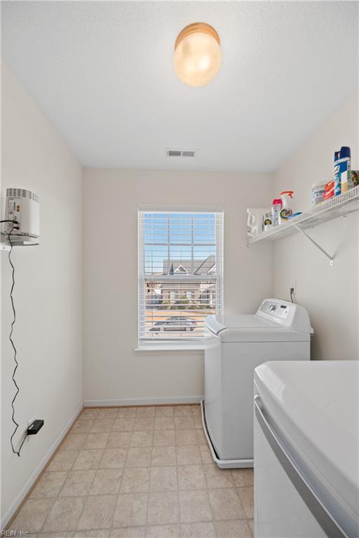 laundry room with laundry area, visible vents, washer and clothes dryer, and baseboards