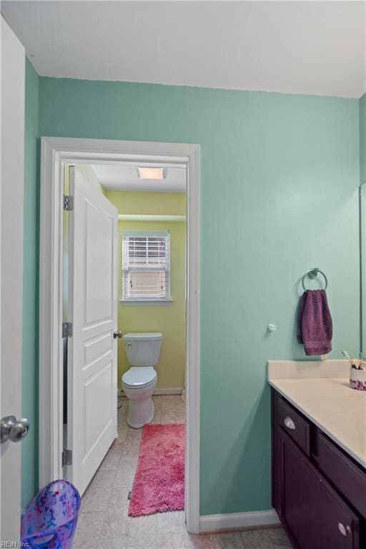 bathroom featuring toilet, baseboards, and vanity