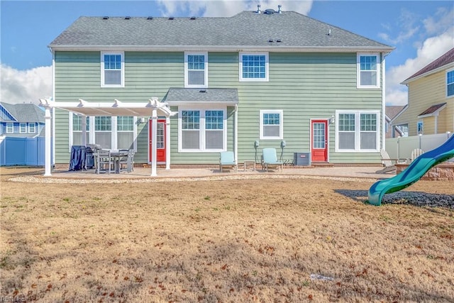 rear view of property featuring roof with shingles, a lawn, a patio area, and fence