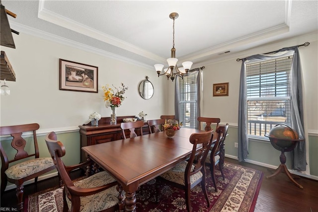 dining area with a notable chandelier, a raised ceiling, visible vents, ornamental molding, and wood finished floors