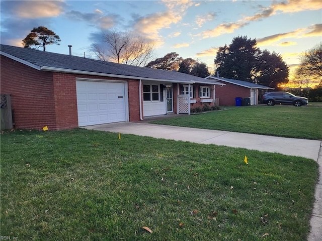 single story home with a garage, concrete driveway, a lawn, and brick siding