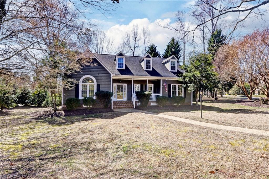 cape cod house featuring a porch and a front lawn