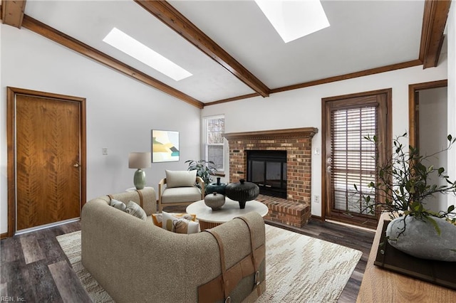 living room featuring vaulted ceiling with skylight, a brick fireplace, dark wood-style floors, and a healthy amount of sunlight