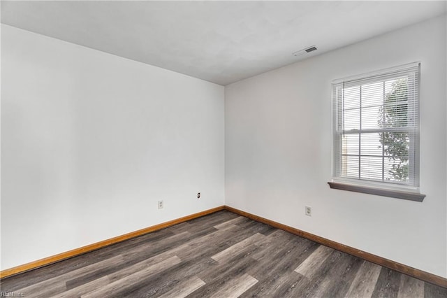 spare room featuring visible vents, baseboards, and dark wood-style flooring