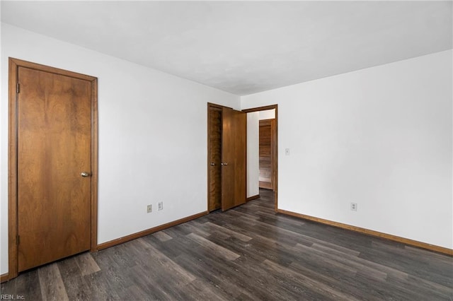 spare room featuring baseboards and dark wood-style flooring