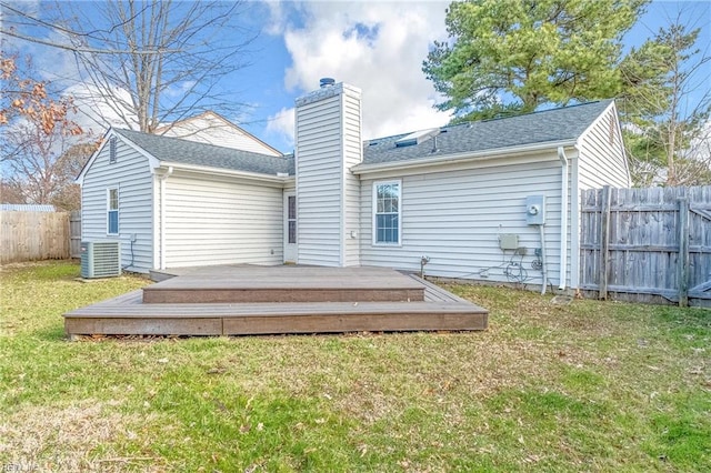 back of property featuring fence, a wooden deck, a yard, central AC, and a chimney