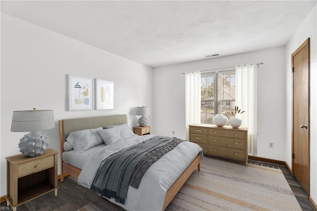 bedroom with visible vents, baseboards, and wood finished floors